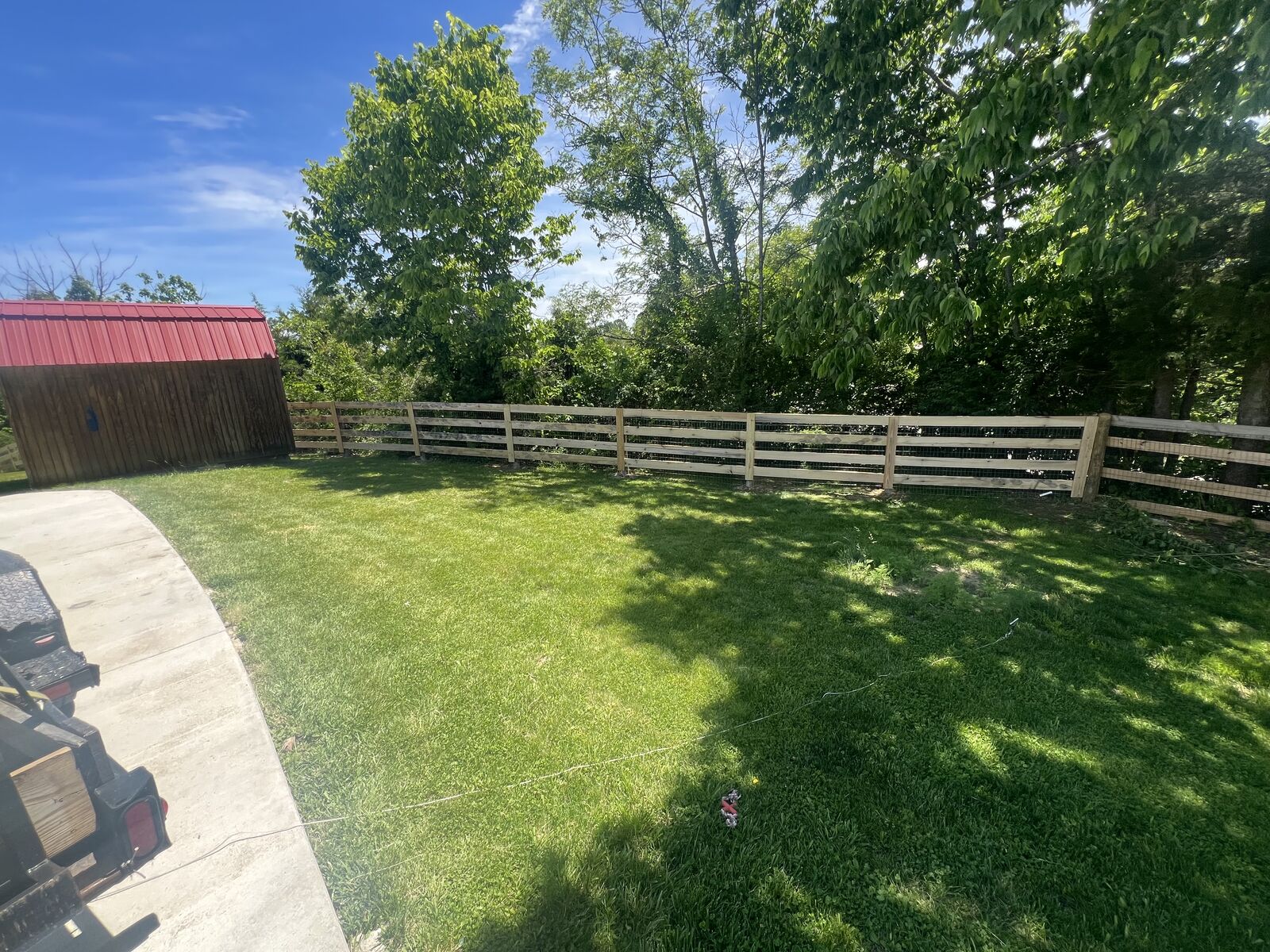 Four-board wood fence along a backyard property line