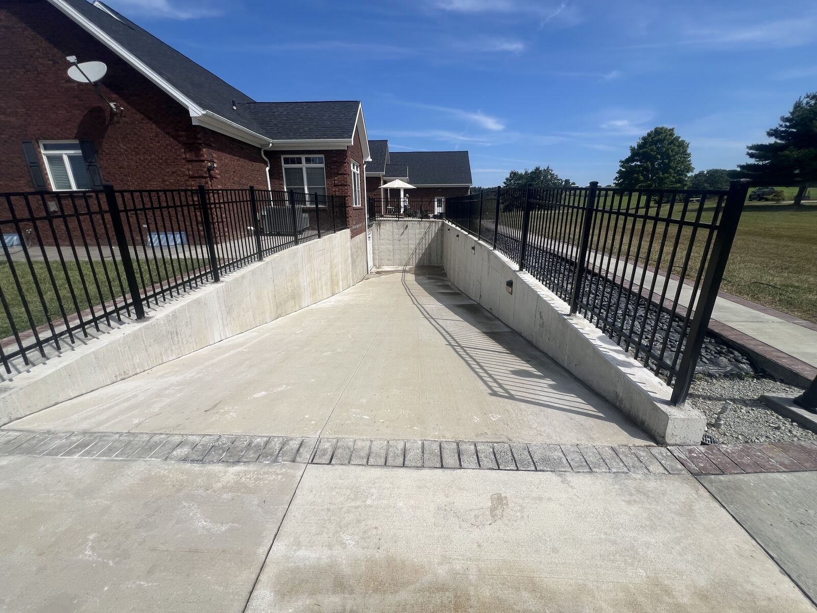 Black aluminum fencing along both sides of a concrete ramp